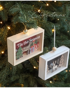 Close-up of wooden Christmas shadow box hanging on tree with deer and festive message