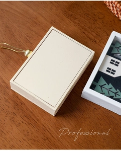 Macro view of cream wooden holiday ornament box with gold hanging string and bead