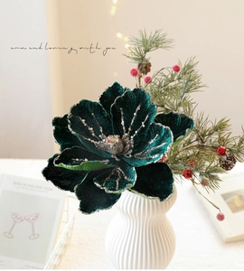 Close-up of velvet magnolia flower in dark green with golden glitter in a ceramic vase