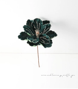 Detail of dark green velvet artificial magnolia flower with silver glitter on white background