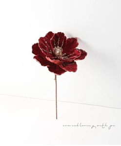 Detail of red velvet artificial flower with gold glitter and sequins on a long stem