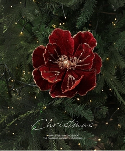 Close-up of velvet red Christmas flower with gold sequins on a lit Christmas tree