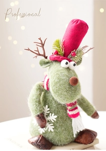 Detail of felt Christmas reindeer decoration with red hat and striped scarf on warm background