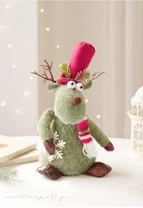 Detail of plush Christmas reindeer with green fur, red hat and snowy pine needle accents