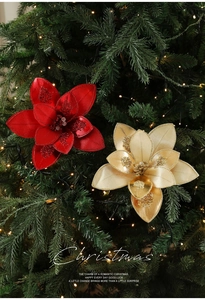 Detail of red and gold glittery Christmas flowers on a festive tree with warm lights
