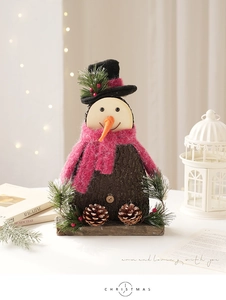 Detail of wooden snowman ornament with a red scarf, black hat, and natural pine cones