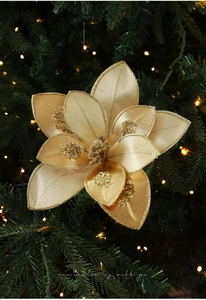 Detailed view of 15cm gold glitter fabric Christmas flower on green pine branches