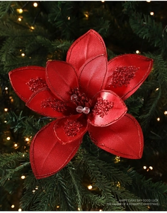 Detailed view of red fabric Christmas flower with glitter edges and beads on a tree