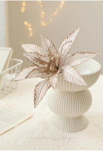 Close-up of champagne gold glitter artificial poinsettia flower in white ribbed vase