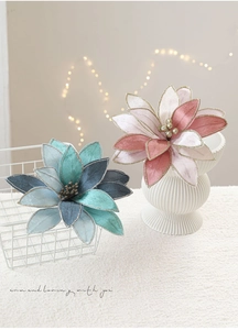 Detailed close-up of decorative fabric Christmas flowers with golden edges and pearls