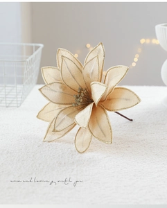 Close-up of champagne fabric poinsettia with gold glitter edges and decorative stem