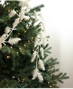 Detailed view of white feather Christmas ornaments on a festive tree with warm lights