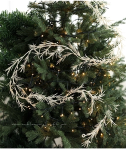 Detail of warm LED string lights on white artificial branch for Christmas tree decor