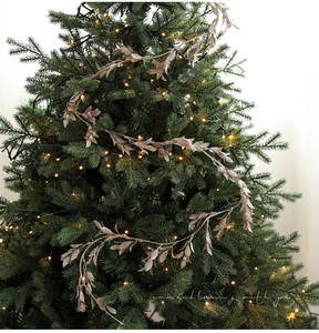 Champagne gold glitter leaf garland draped over a Christmas tree with warm LED lights
