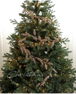 Close-up of champagne gold glittery pine branches on a lit Christmas tree