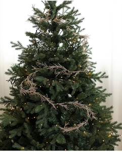 Close-up of golden Christmas garland with glitter finish on tree with warm lights