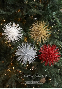Sparkling starburst ornaments in gold, red and silver on a decorated Christmas tree branch