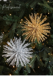 Close-up of sparkling glitter star ornaments on a green Christmas tree with warm lights