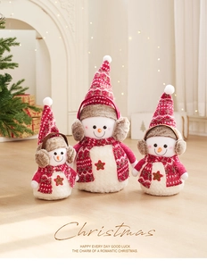 Trois bonhommes de neige en peluche avec bonnets rouges dans un décor de Noël chaleureux