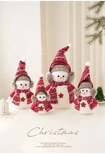 Détail de quatre bonhommes de neige en peluche blanche avec bonnets et écharpes rouges