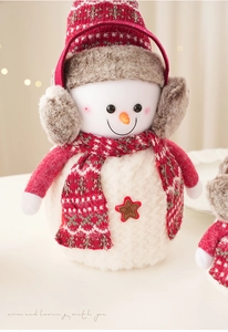 Gros plan détaillé du bonhomme de neige en peluche avec bonnet et écusson Welcome