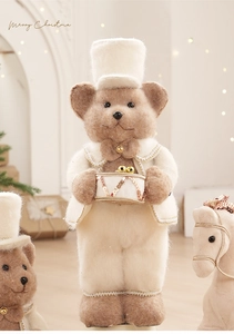Close-up of plush Christmas bear in cream suit with drum and festive holiday details