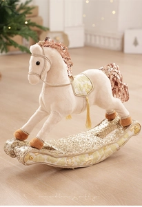 Detail of plush rocking horse with golden sequins and tassels on a cozy holiday background