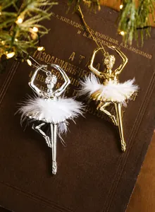 Close-up of gold and silver ballet girl ornaments with white feathers on vintage book