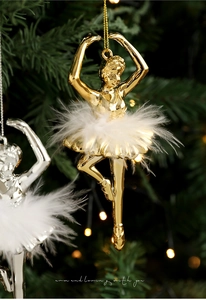 Close-up of golden ballet girl ornament with feather skirt hanging on a Christmas tree