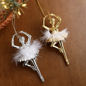 Golden and silver ballerina Christmas tree ornaments with white feather skirts on wood