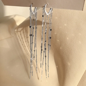 Detail of silver long tassel earrings with polished round sequins and metal chains