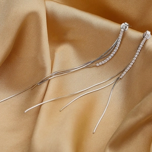 Close-up of s925 silver fringe earrings with sparkling crystals on golden silk fabric