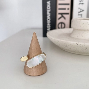Bague ouverte élégante dorée avec incrustation de nacre ovale sur support en bois