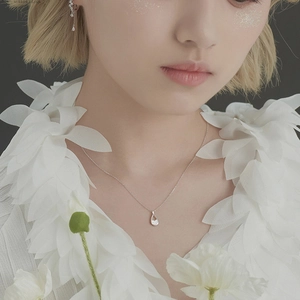 Detailed view of silver teardrop pendant necklace and matching earrings on female model