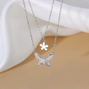 Macro detail of silver double-layer necklace with zircon butterfly and flower charms