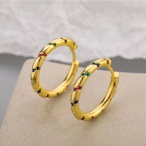 Detail of gold twisted huggie earrings featuring diagonal rainbow zircon inlay work