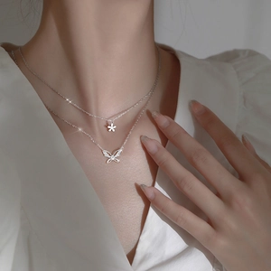 Double-layered silver necklace featuring zircon butterfly and floral pendants on a model
