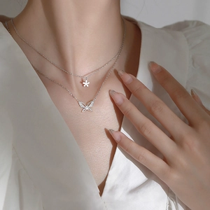 Macro detail of silver double-layered necklace with zircon butterfly and flower pendants
