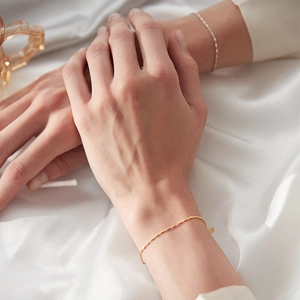 Close-up of a minimalist gold geometric chain bracelet on a silk background