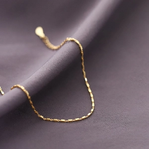 Macro shot of minimalist gold geometric rectangular chain links on purple velvet fabric