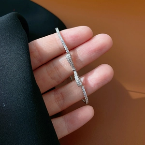 Adjustable S925 silver bow bracelet with cubic zirconia inlay worn on a wrist