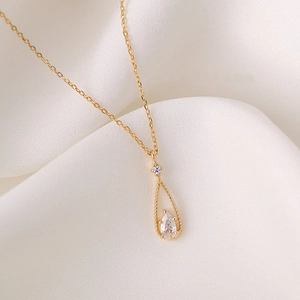 Elegant gold teardrop zircon pendant necklace for women on white luxury silk background