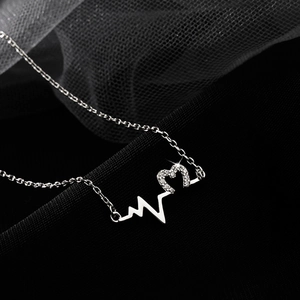 Detailed close-up of 925 silver heart necklace with sparkling pavé stones on black mesh