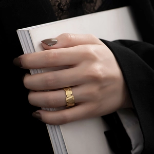 Close-up of golden irregular textured ring worn by a model against a black suit