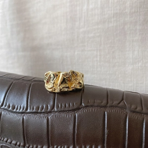 Macro shot of gold minimalist ring with irregular lava texture on brown leather