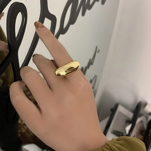 Minimalist golden bean ring on female hand with a polished metallic finish