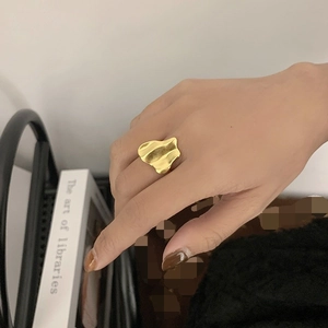 Minimalist gold irregular wave ring with artistic lava flow design on model's hand