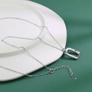 Minimalistische silberne Halskette mit rechteckigem Anhänger auf Keramikschale