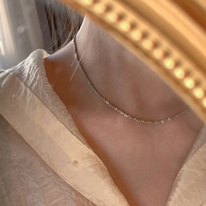 Close-up of sparkling S925 sterling silver tennis necklace on a model with vintage mirror