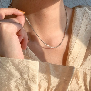 Glistening S925 sterling silver snake chain necklace on model with warm sunlight reflection